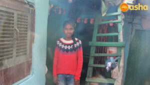 Pooja standing in front of her shanty in Asha's Anna Nagar slum community