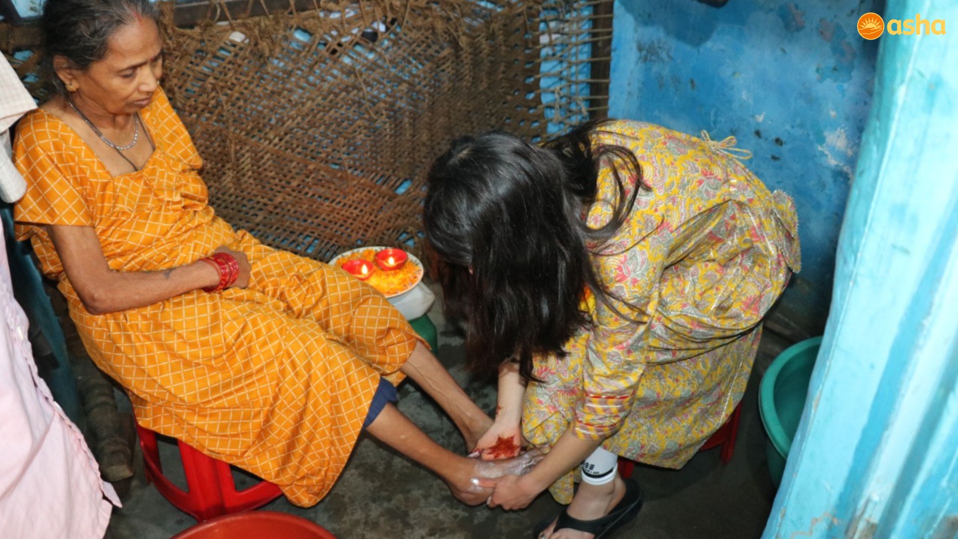 Julianna, Asha volunteer from Boston, tenderly Washes the feet of an Elderly Woman at her Small Shanty in Zakhira Slum Community